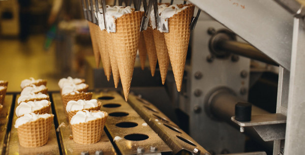 Vanilla ice cream inside cones which are attached to a machine